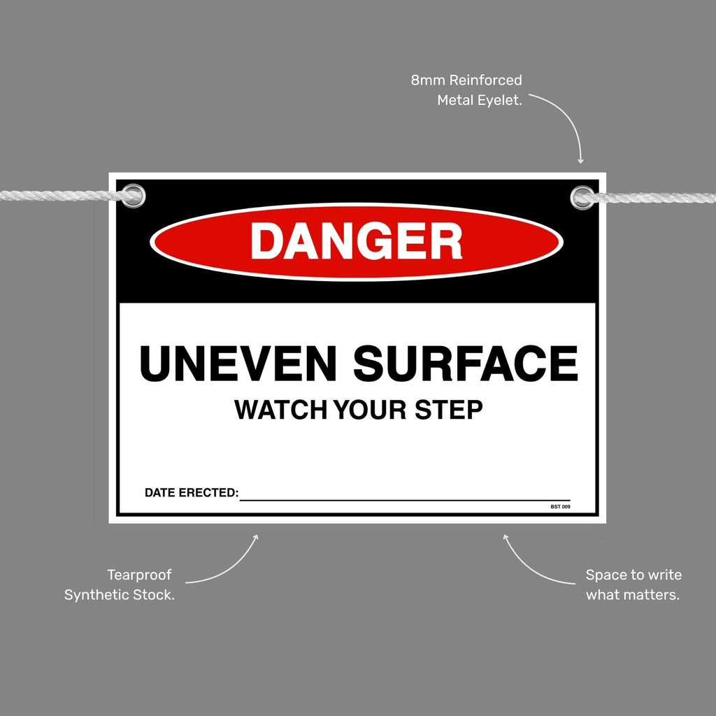 Danger Uneven Surface Watch Your Step flag tag with callouts showing the 8mm reinforced metal eyelet, tearproof synthetic stock and write in space.